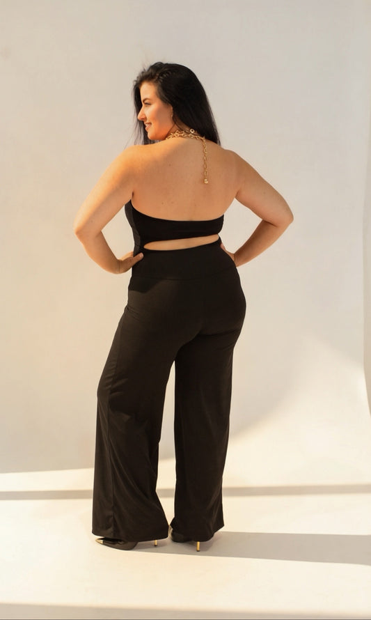 Woman wearing a black outfit with wide-leg pants and a halter top against a white background
